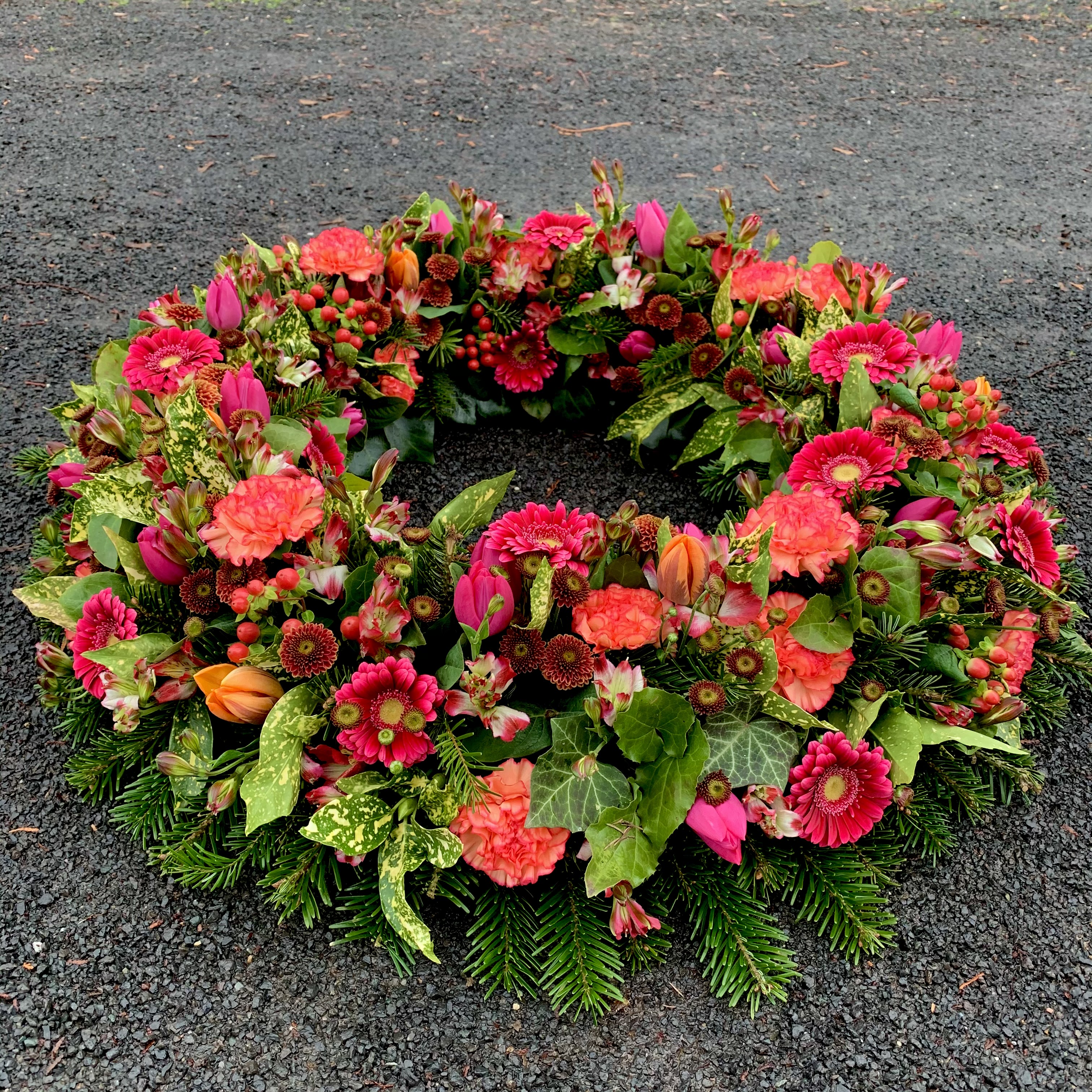 Rundgesteckter Kranz in orange-rot-pink Farbtönen 